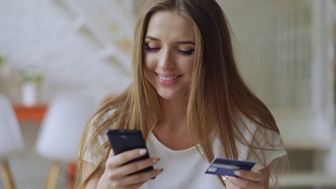 Woman smiling while browsing cannabis products on her phone for online shopping