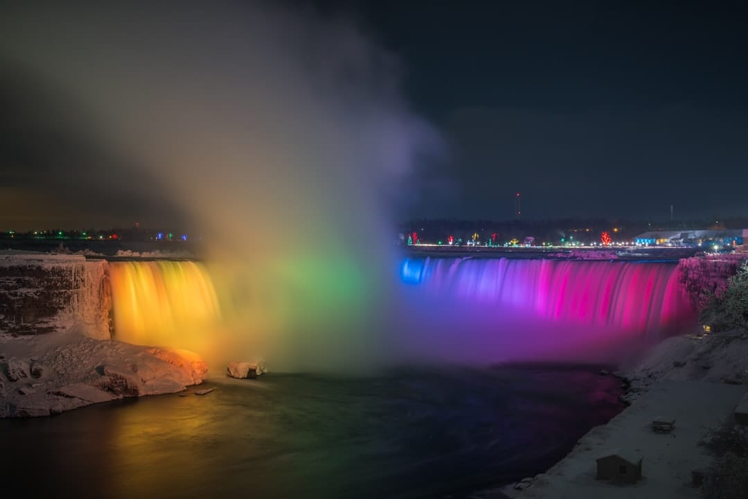 Niagara Falls lit up at night with city buildings and lights in Ontario