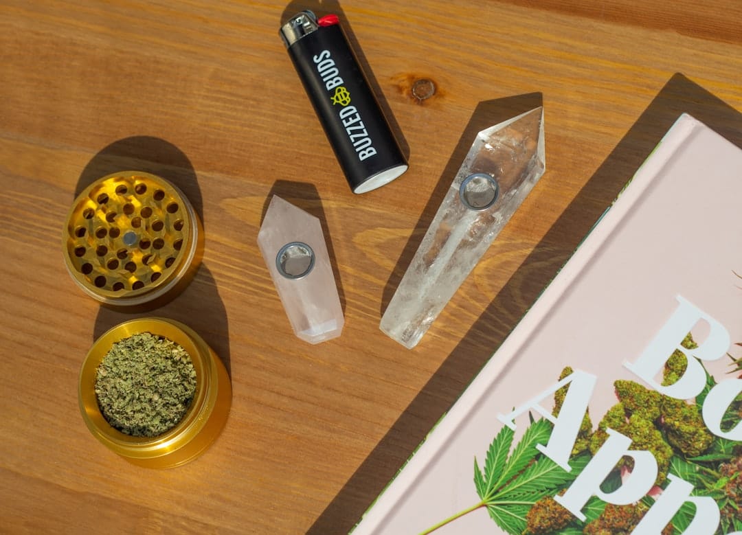 Cannabis accessories including grinder and supplies arranged on a wooden table