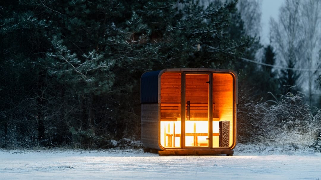 Warm cozy cabin illuminated in a snowy forest during winter dusk, perfect setting for relaxing with cannabis