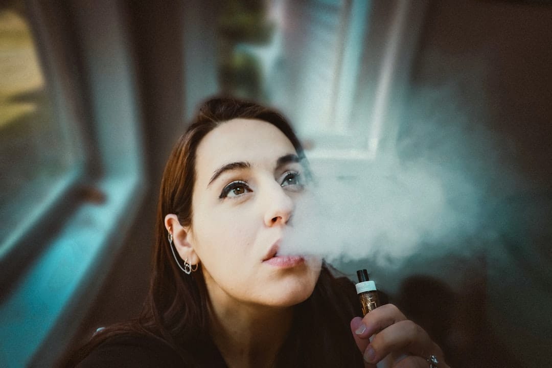 Woman holding a gold cannabis oil vaporizer pen demonstrating vaping technique