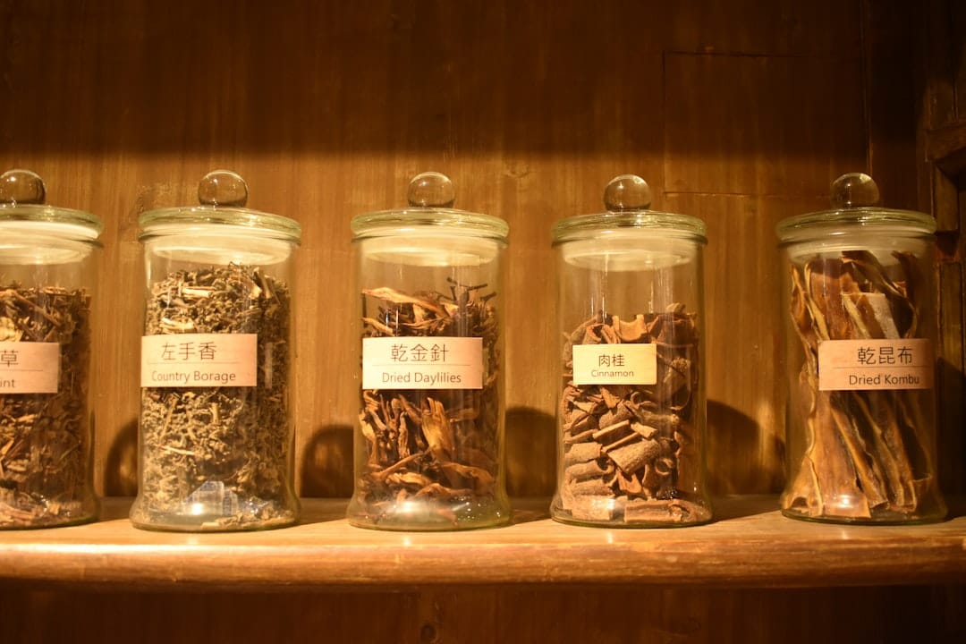 Glass jars filled with dried herbs on a wooden shelf illustrating proper cannabis storage for keeping ounces fresh