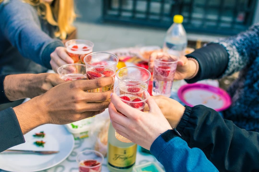 Friends raising clear glasses in a cheers toast celebrating with cannabis beverages