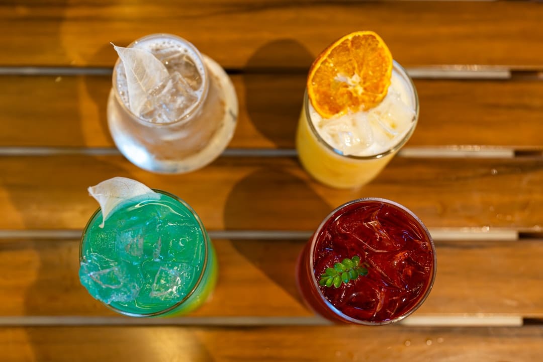 Four colourful drinks on a wooden surface showing different ways to mix THC syrup