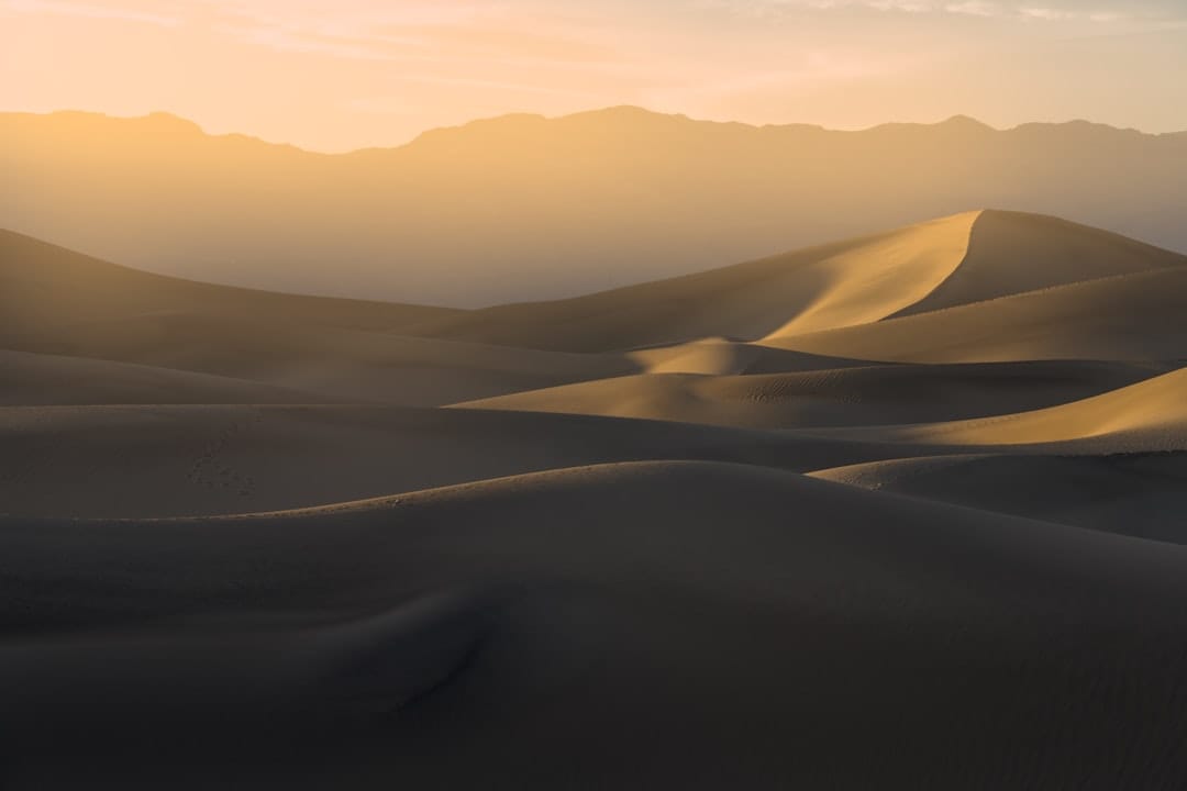 Sweeping desert sand dunes with distant mountains symbolising the Death Valley OG strain origins