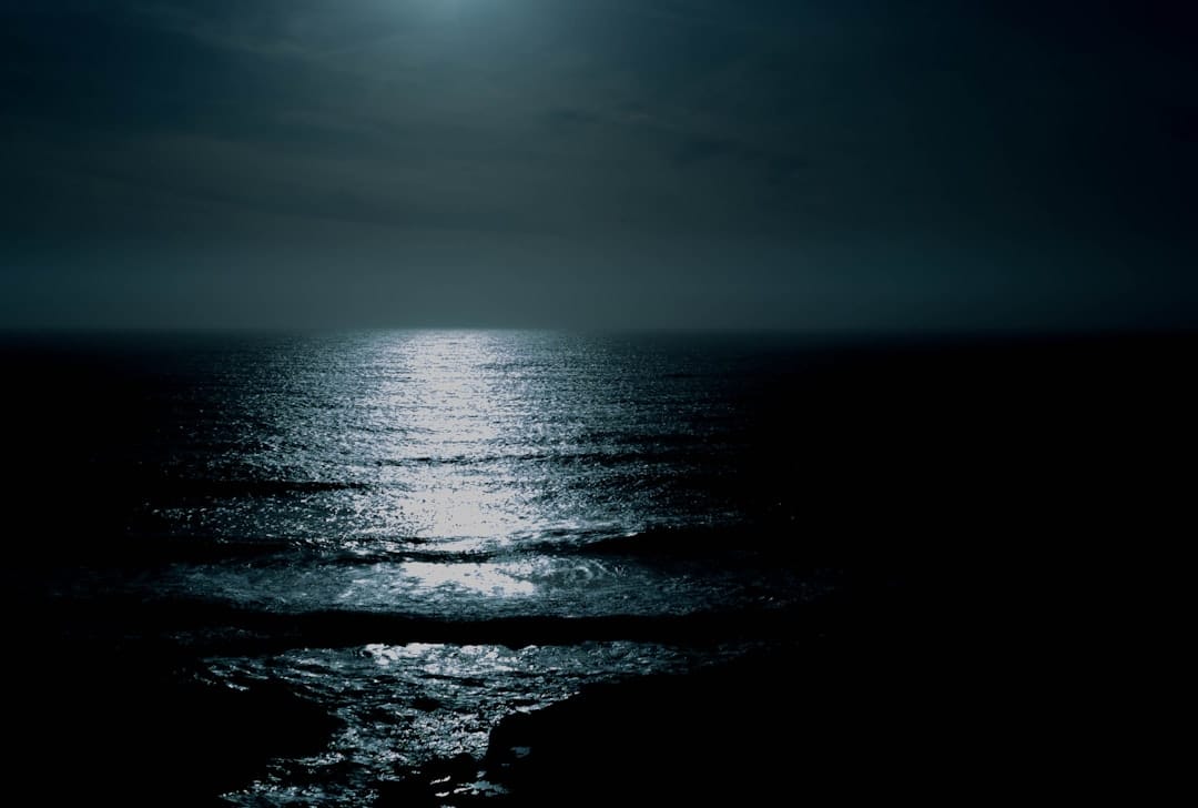 Body of water under moonlit cloudy sky at night representing calm evening indica experience