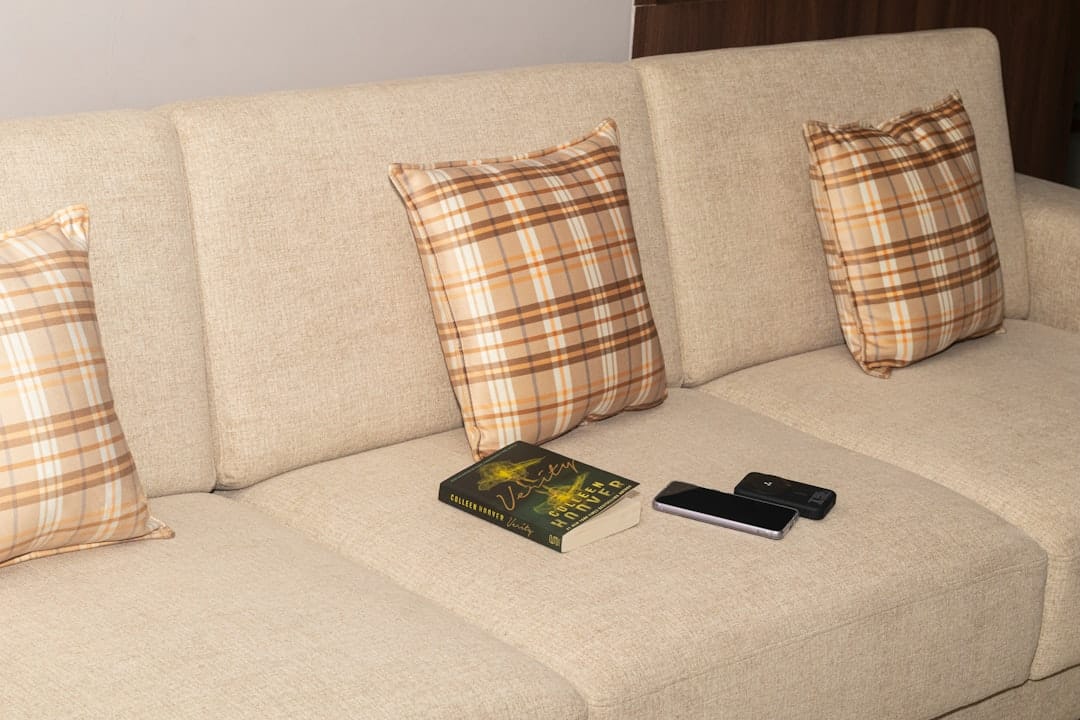 Cream sofa with cozy plaid pillows and books for a relaxing evening at home
