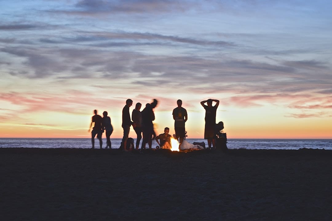 Group of friends gathering around a campfire outdoors enjoying an evening together