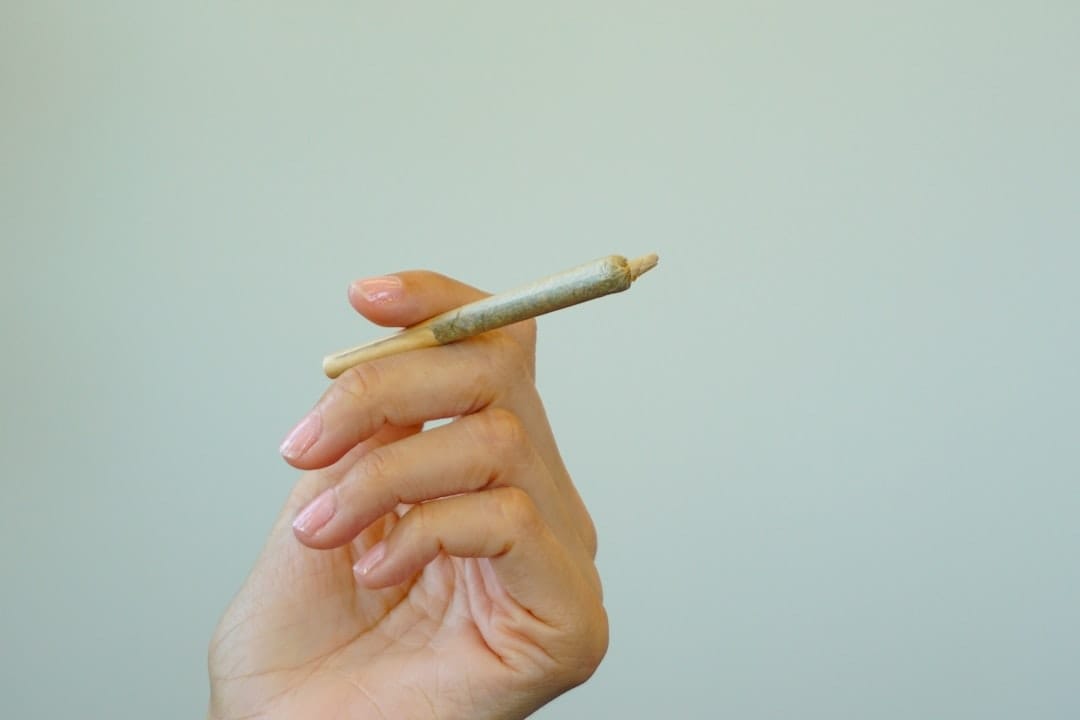 Hand-rolled cannabis kief pre-roll joint held between fingers