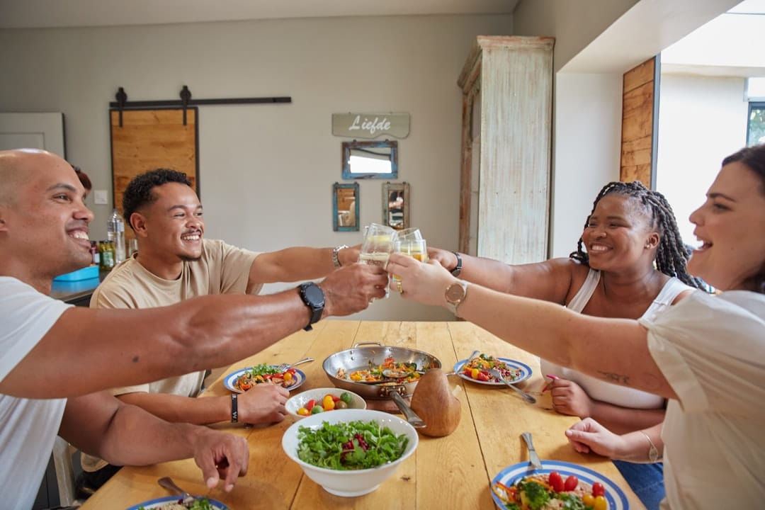 Friends sharing a meal around a wooden table for cannabis food pairing dinner party