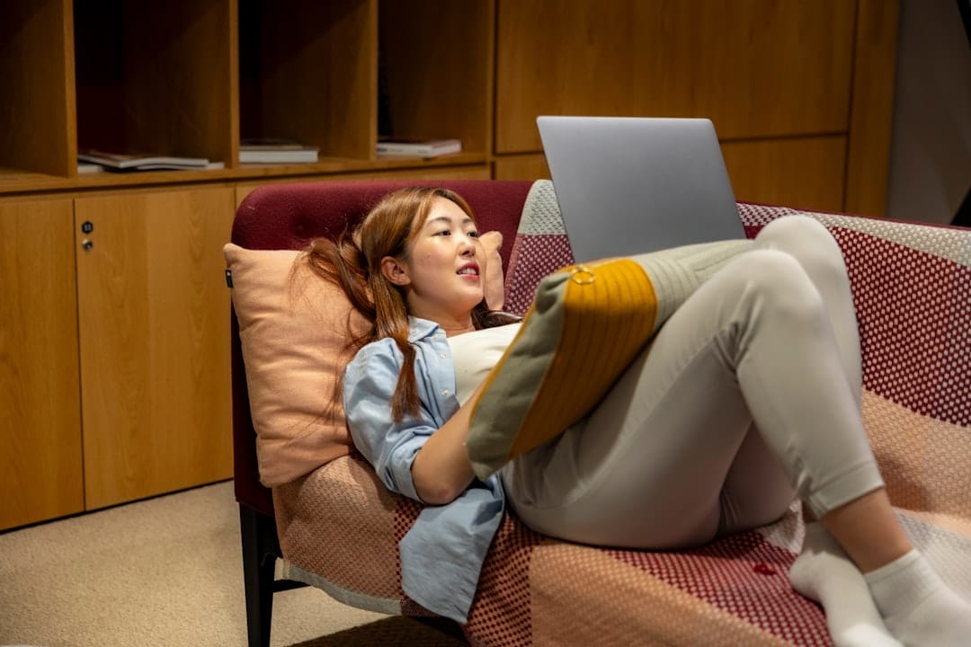 Person relaxing on couch browsing cannabis products online on a laptop
