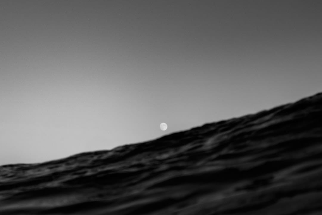 Full moon rising over dark ocean waves at dusk, creating a calm and restful atmosphere