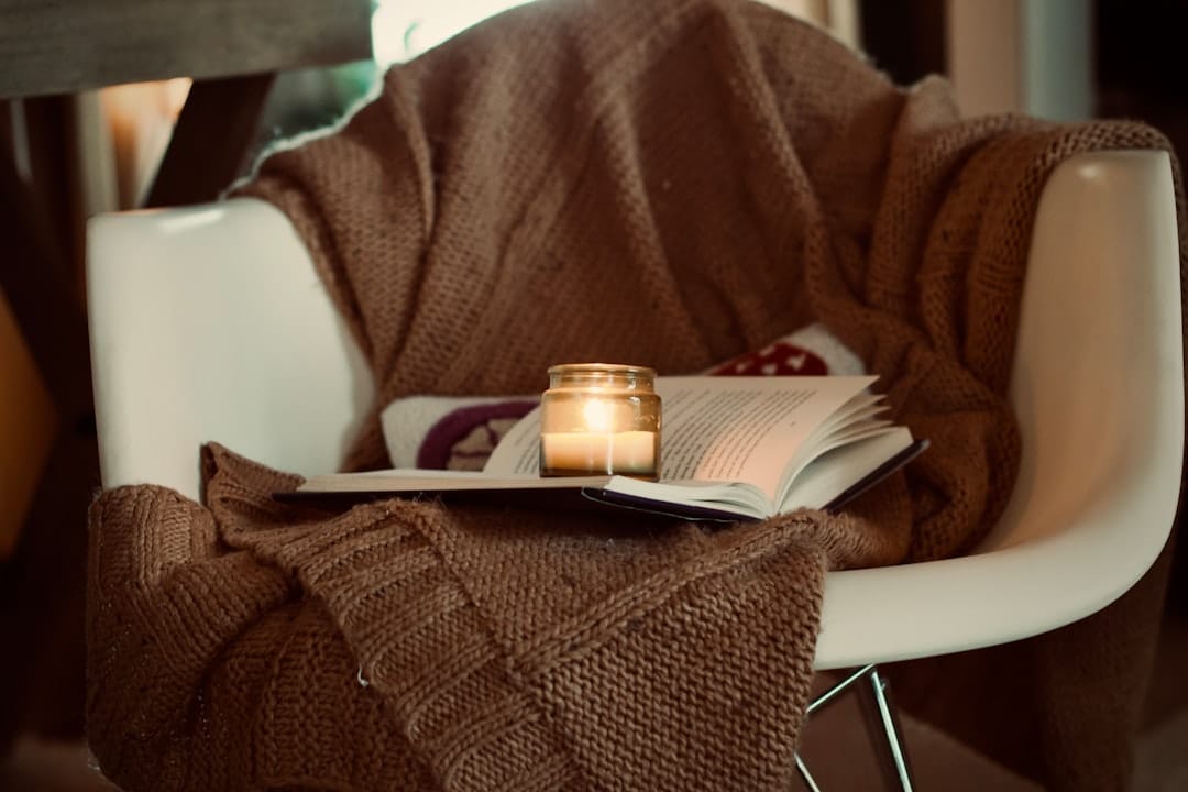 Cozy candle and book on a chair for a relaxing evening at home