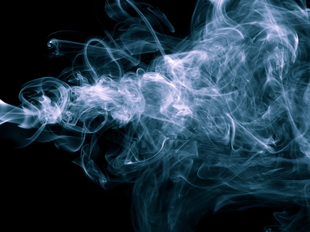 Blue vapour smoke swirling against a dark background representing THC vape cloud
