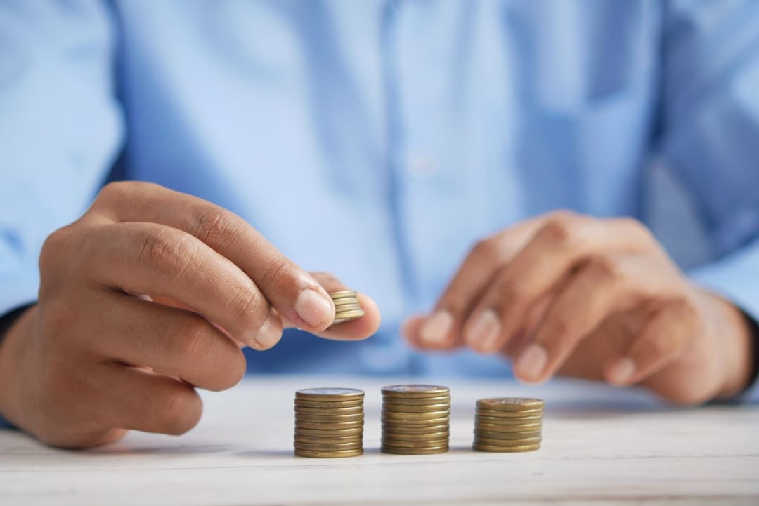 Person stacking coins on a table illustrating savings from buying cheap ounces of weed online in Canada