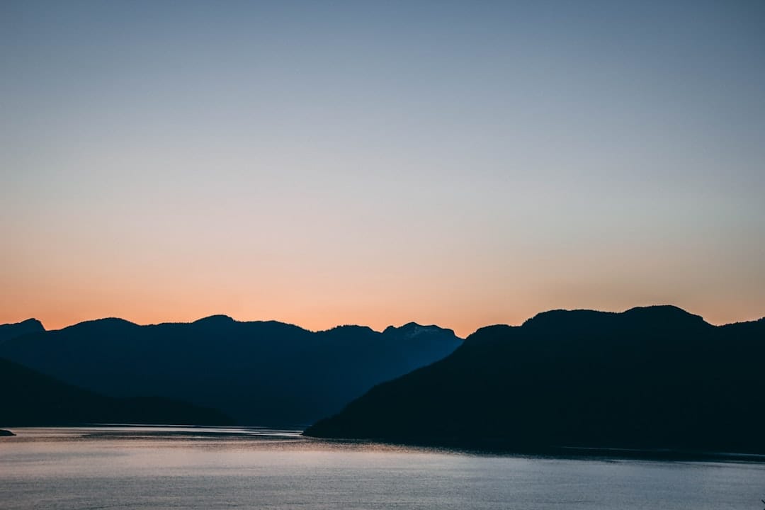Silhouette of mountains near water during a golden sunset in British Columbia
