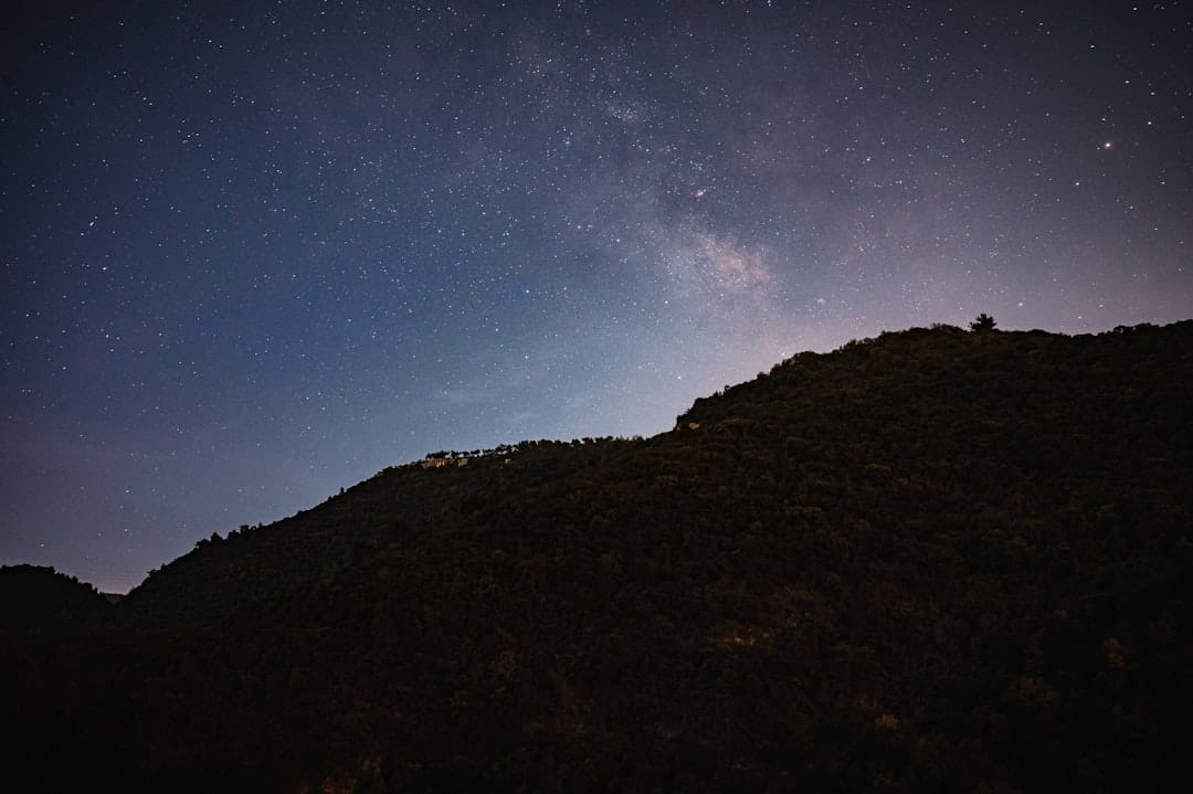 Starry night sky over dark mountain silhouette evoking peaceful sleep and relaxation