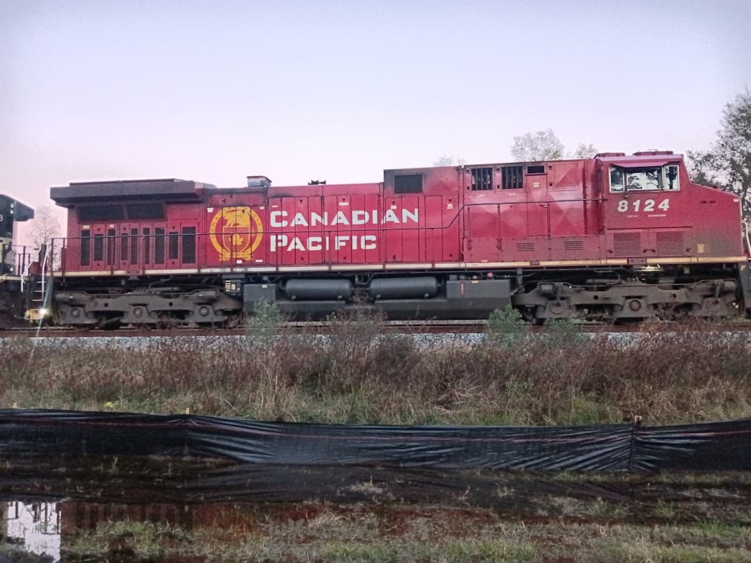 Red Canadian Pacific train on tracks through prairie landscape