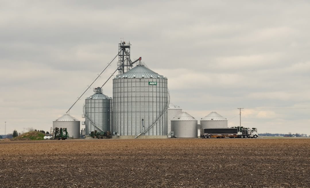 Large grain silos with trucks in rural Saskatchewan prairie setting