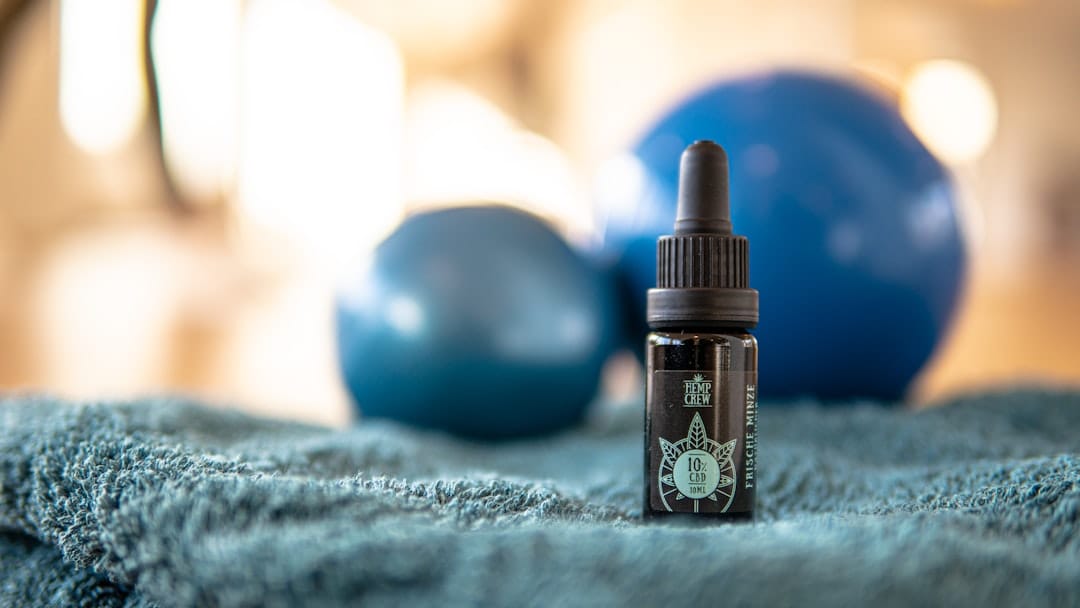 CBD oil dropper bottle with floral background representing CBD gummies for wellness in Canada