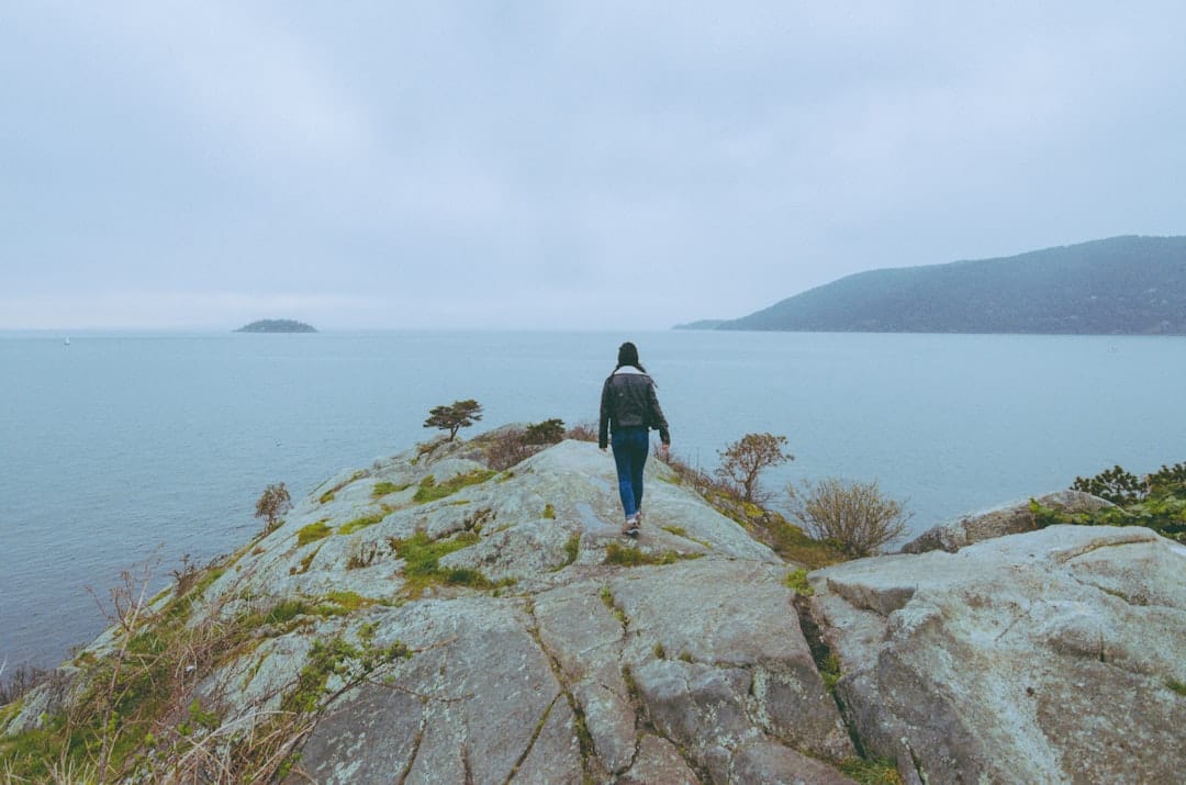Person standing on rocks beside the Atlantic Ocean on the Cape Breton coast near Inverness, Nova Scotia