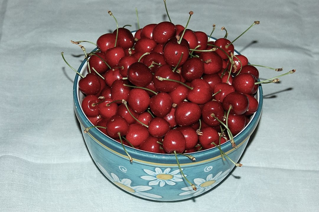 Bowl of fresh red cherries on a wooden surface representing the sweet cherry flavour of Cherry Pie hash