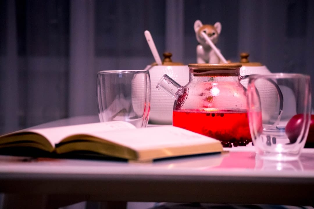 Glass of herbal tea beside a book as a relaxing evening ritual alternative during a tolerance break