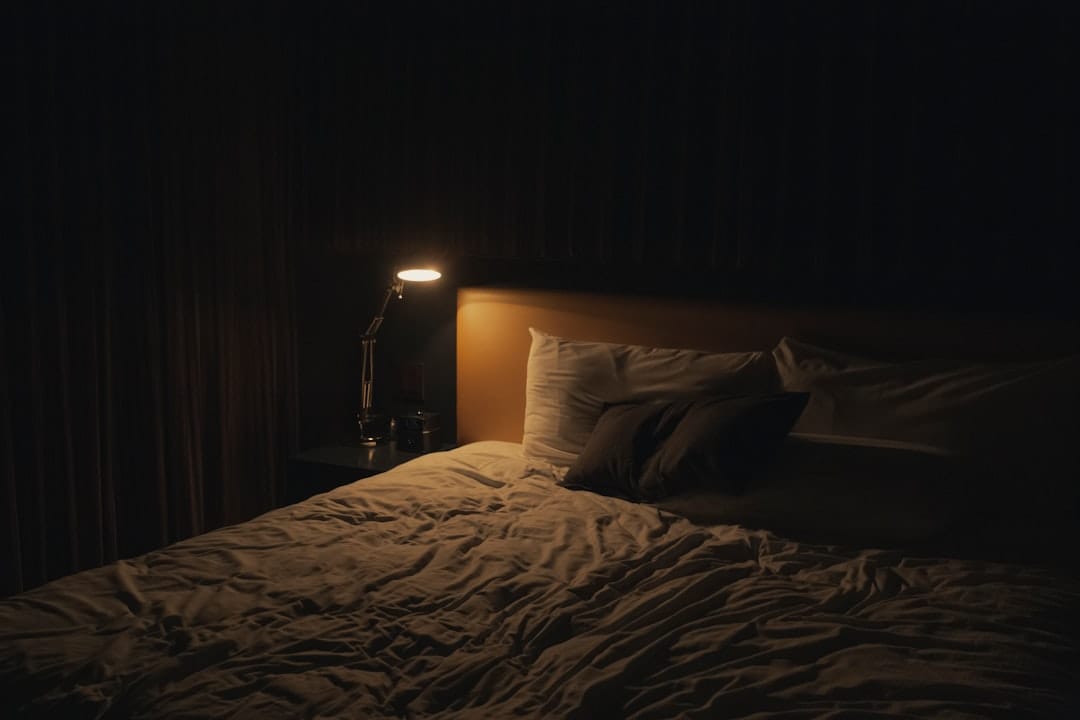 Warm bedside lamp on nightstand in a cozy bedroom setting for cannabis edibles and sleep