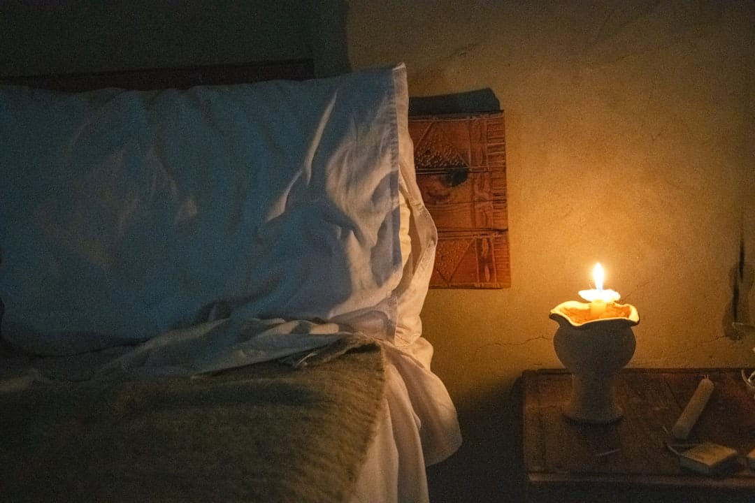Cozy evening relaxation setting with lit candle by the bedside