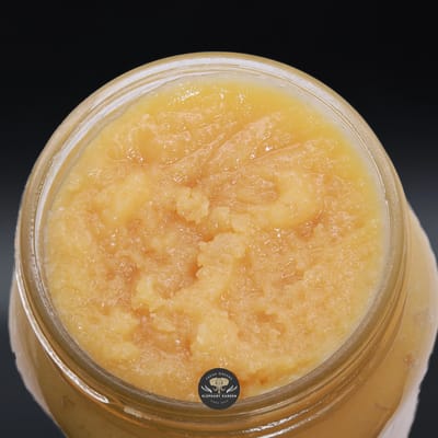 Pink Cookies live resin concentrate, pale golden sugary sauce in an open glass jar, top-down view