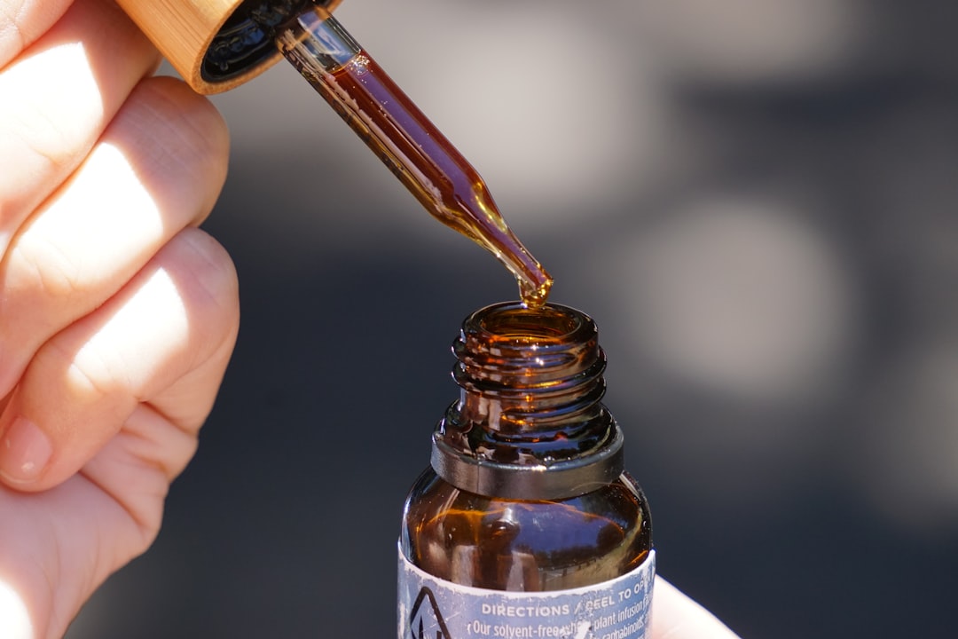 Person holding a brown glass CBD oil tincture bottle