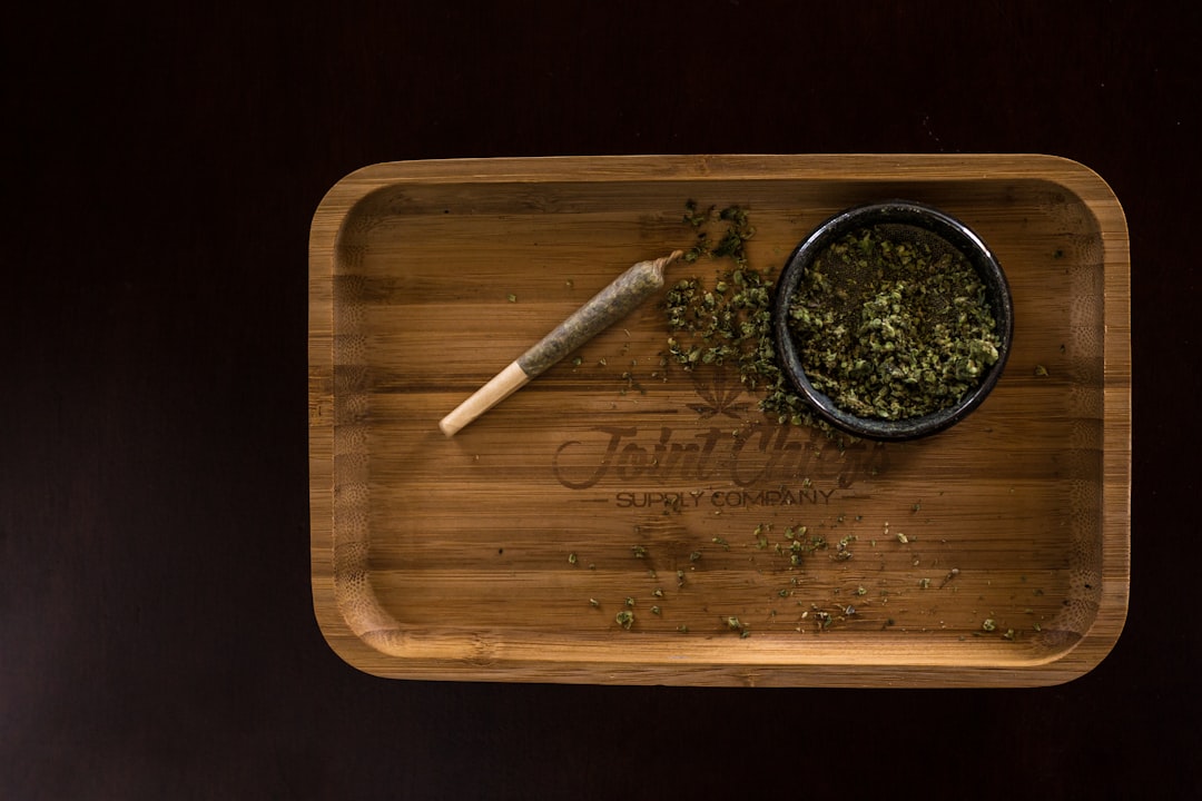 Cannabis flower and rolling papers on a wooden tray, ready for preparing a hash-topped joint