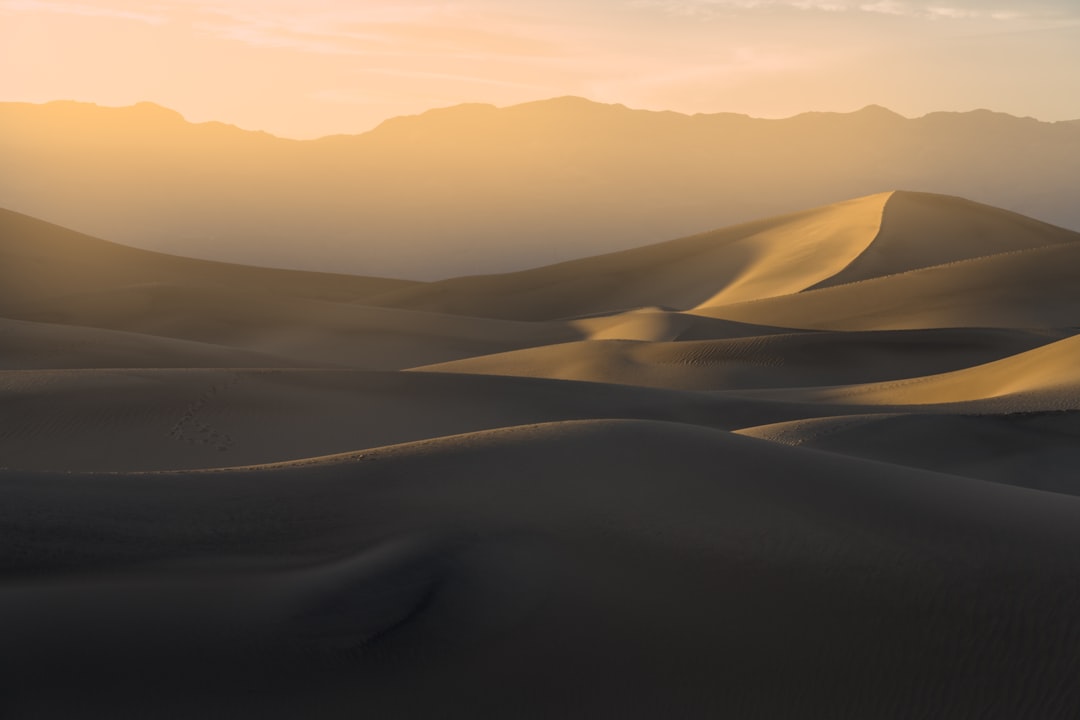 Sweeping desert sand dunes with distant mountains symbolising the Death Valley OG strain origins