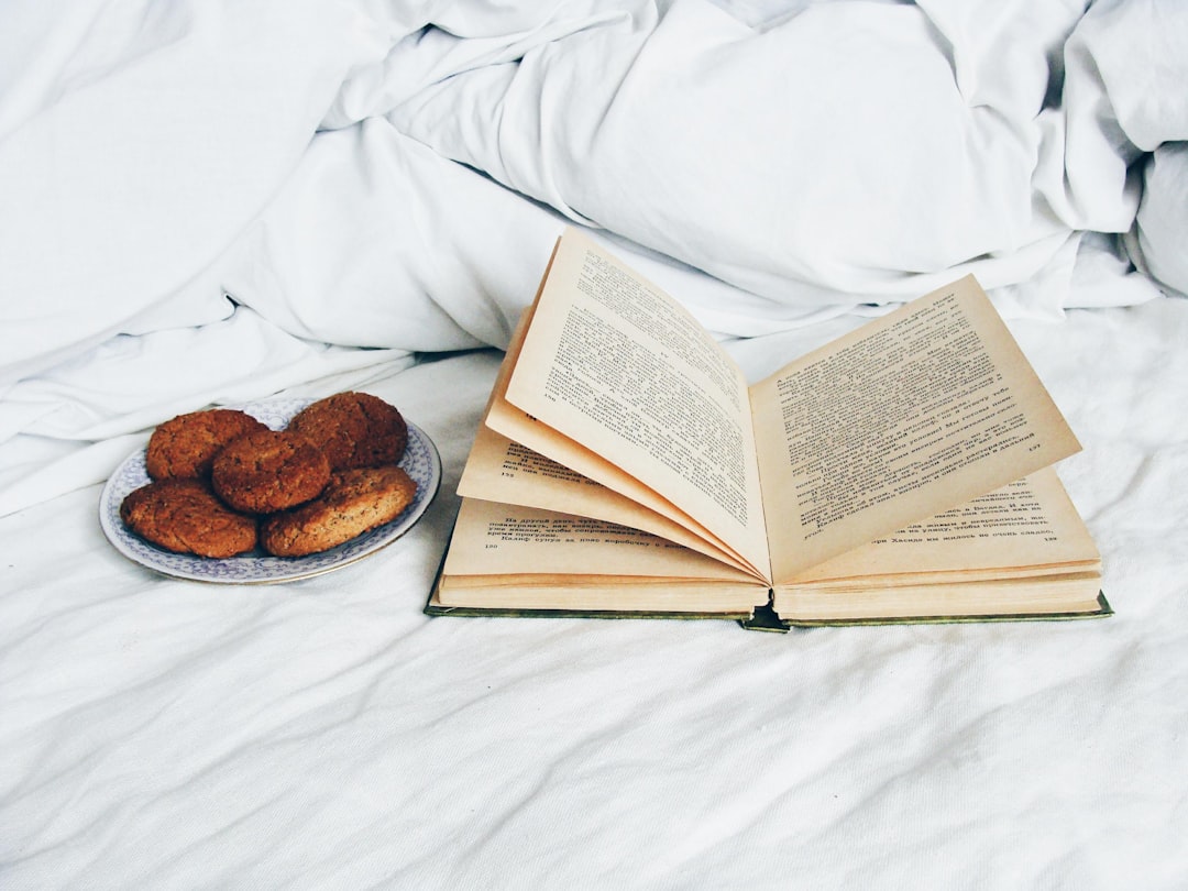 Open book and cookies on a cozy white bed for a relaxing evening with edibles
