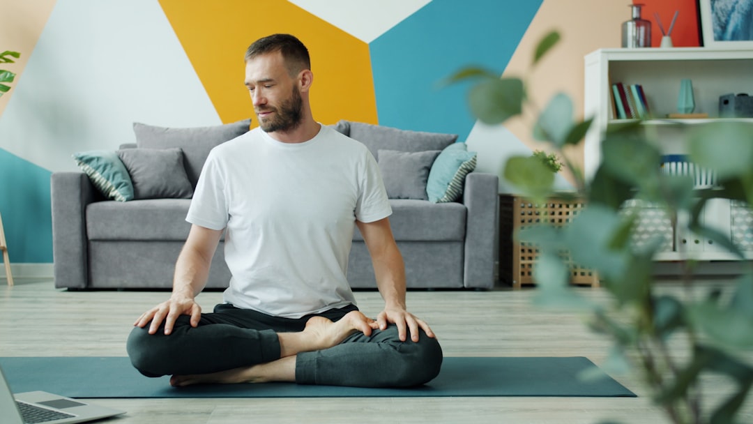 Man meditating in lotus position on yoga mat representing daily CBD wellness routine